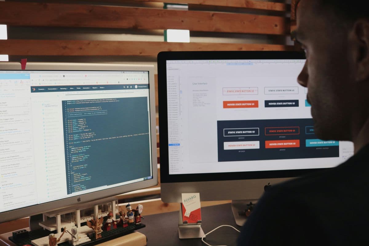 Engineer reviewing code and interface design on two monitors